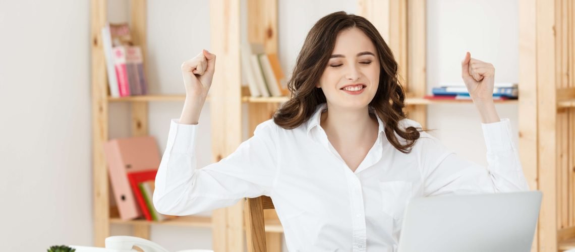 Portrait of smiling pretty young business woman sitting on workplace.